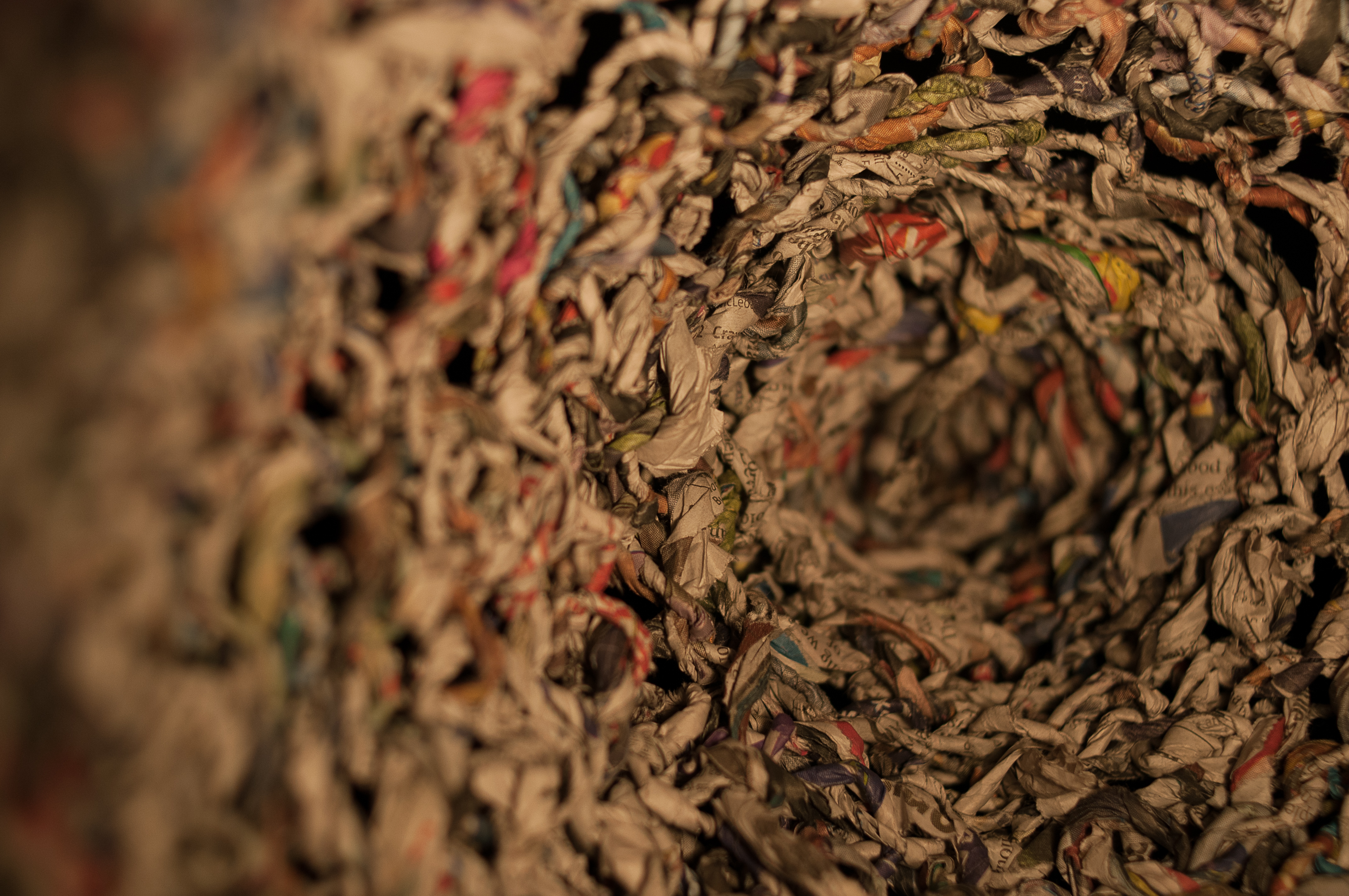 A photograph of the inside of the crocheted shape. It is possible to see the loops of the crochet technique, and also to see the colours from the newspaper ink.