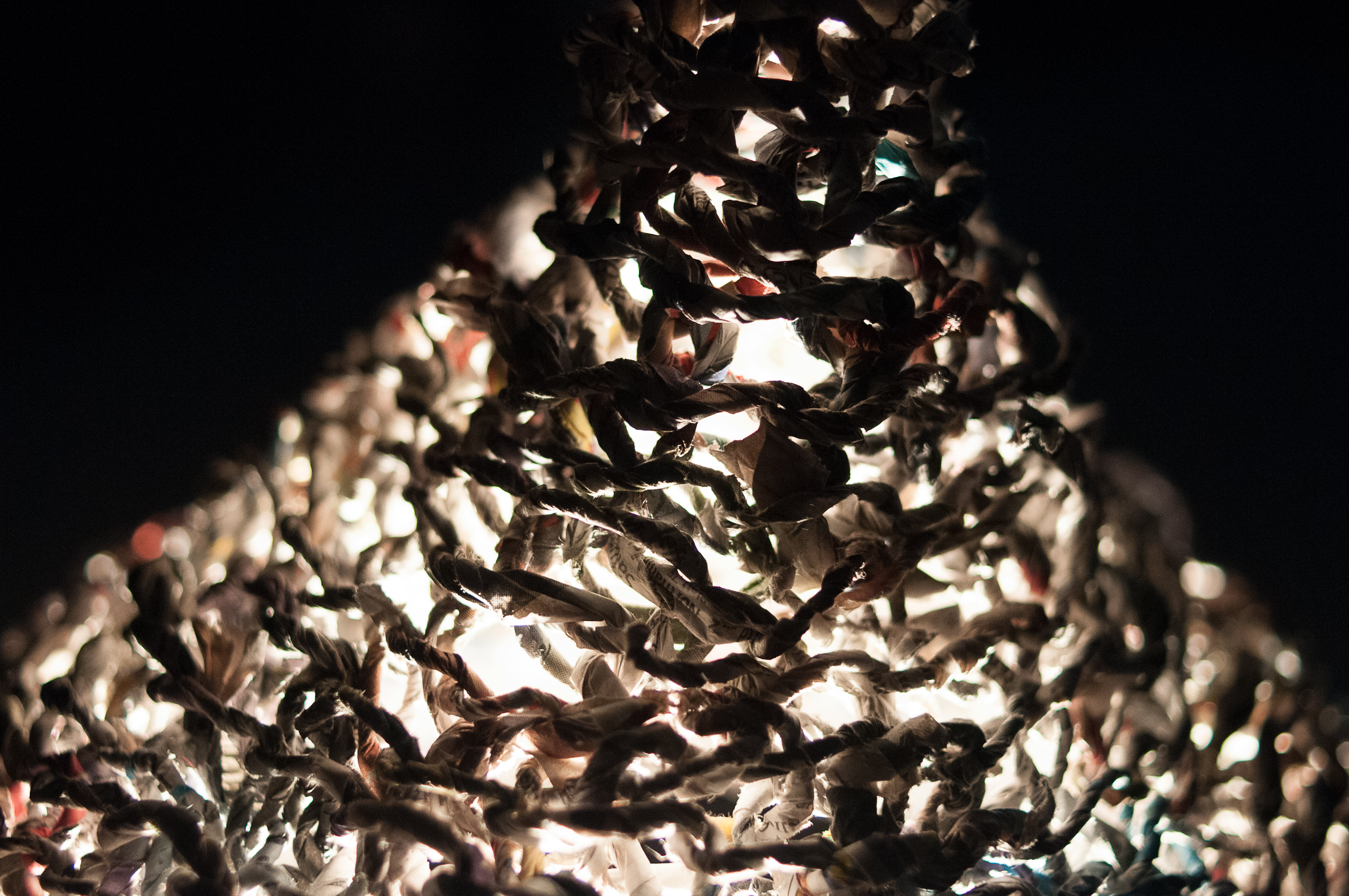 A photograph of a shape crocheted from yarn made of paper. The shape is lit from the inside.